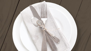 plate setup with fork, knife, spoon and napkin on dark grey wood