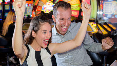 man and woman excitedly winning at a slot machine